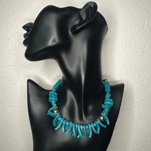 Boho vintagehalsband m turkos halvädelsten/Natursten Etno Retro 80-tal 90-tal  - Vintage halsband i boho/etnisk stil från 1980/90-talet. Pärlorna är i turkos nyans, troligen färgad halvädelsten (howlit/magnesit), med mässingsfärgade detaljer. Matt struktur som ger ett rustikt, handgjort intryck. Längd ca 48 cm. Perfekt till sommarens kläder eller för att addera en färgklick till en enkel outfit. Prutning accepteras inte, men jag erbjuder rabatt vid köp av flera saker. Jag rensar smyckesskrin och garderob – passa på att kika på mina andra annonser!  