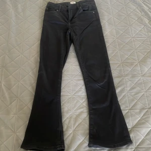 Svarta bootcut byxor från 157, stl 150 - Svarta byxor från 157 i bootcut-modell med klassisk femficksdesign. Byxorna har dragkedja och knapp framtill och är tillverkade i ett mjukt bomullsmaterial med lite stretch. Perfekta för dig som gillar en tidlös och snygg look.