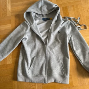 Grå kofta från Polo Ralph Lauren - Nästan helt ny. Använts ett par gånger bara. Är fortfarande i mycket bra skick. Priset kan diskuteras.