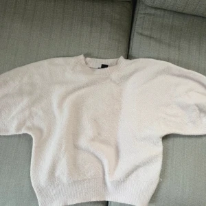 Ljusrosa stickad tröja från Lindex - Supermjuk och fluffig ljusvit stickad tröja från Lindex. Tröjan har rund hals och ärmarna slutar vid armbågarna typ. 