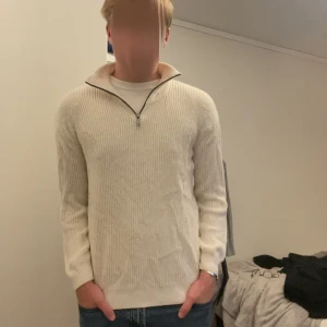 Beige ribbad half zip-tröja H&M - Ribbstickad beige tröja från H&M med half zip-dragkedja och hög krage. Långärmad och i mjukt material som passar perfekt till jeans. Enkel och stilren design som funkar året runt.