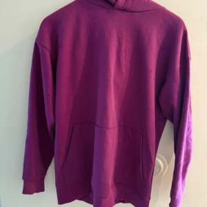 Lila hoodie från FSBN XS - En oversized hoodie i en snygg lila färg från FSBN. Tröjan har huva, magficka och långa ärmar. Relaxed fit för en chill vibe. Perfekt att slänga på sig när du vill vara bekväm men ändå se cool ut.
