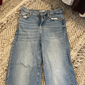 Blå wide jeans från Zara, strl 36 - Säljer ett par ljusblå jeans från Zara i storlek 36. Jeansen har raka och vida ben.