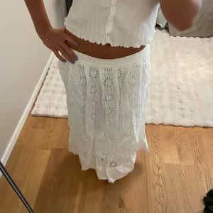 Vit långkjol med broderade blommor - Superfin vit långkjol med broderade blommor och elastisk midja. Kjolen har fickor på sidorna också!💞