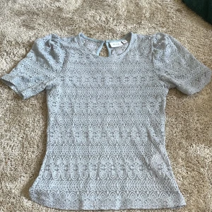 Ljusblå spetsblus från Vila - Superfin ljusblå blus från Vila med korta puffärmar och spetsmönster över hela toppen. 