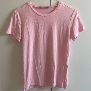 Ljusrosa basic t-shirt - Enkel och stilren ljusrosa t-shirt med rund hals och korta ärmar. Perfekt för en chill look och lätt att matcha med jeans eller shorts. Mjuk och skön känsla tack vare bomullsmaterialet.