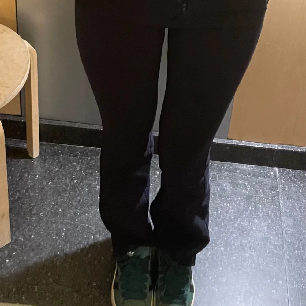 Snygga mörkblå bootcut byxor med låg midja. Perfekta för en stilren look. Byxorna har en klassisk design med dragkedja och knapp framtill.. Farkut & Housut.