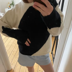 Marinblå och vit stickad tröja - Säljer en mysig stickad tröja i blått och vitt. Tröjan har en unik design med stora blockfärger och långa ärmar. Perfekt för kyliga dagar och en stilren look.