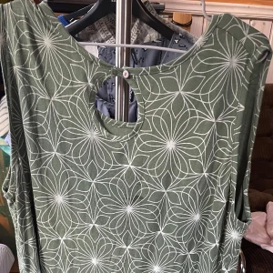 Cassiopea mönstrad grön vit stl 40 - En beg. grön klänning med ett vitt blommönster. Klänningen är ärmlös och har en rund halsringning med en liten öppning bak. Perfekt för en avslappnad stil. Företaget är Danskt och finns i Hvidovre Köpenhamn. Modehuset är KSK fashion.