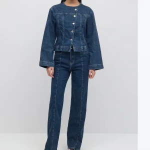 Mörkblå jeansjacka med knappar - Snygg mörkblå jeansjacka med silverfärgade knappar framtill. Matchande jeans till. Jackan är i storlek 38 och jeansen är i storlek 40. Enbart använt en gång och är i gott skick. 