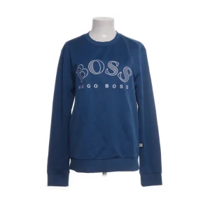 Blå sweatshirt från Hugo Boss - Snygg blå sweatshirt från Hugo Boss med stort BOSS-tryck på framsidan. Tröjan har långa ärmar och en klassisk rund halsringning. Perfekt för en avslappnad stil.