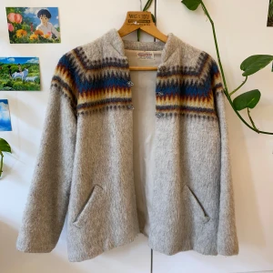 Handvävd jacka/kofta i ull - Handvävd jacka/kofta från Norge. Väldigt varmt material menat för vintertider. Gammal i använt skick. Ett spänne saknas (se bild fem) och den har haft några hål i sömmen som jag lagat. Superfin men tyvärr för kort i ärmarna för mig, skulle inte säga att den är storlek 42 utan snarare S. Jättekul om den kommer till någon som uppskattar den.