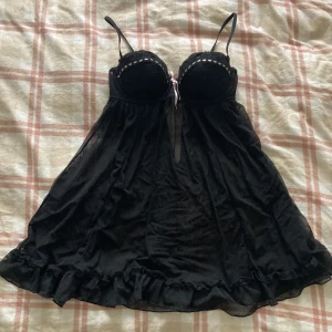 Svart spetsklänning med volangdetaljer - Säljer en elegant svart nattlinne med spetsdetaljer och volangkant. Den har tunna axelband och en söt rosett framtill 💗 Uppskattar B-kupa ! Priset går att diskuteras