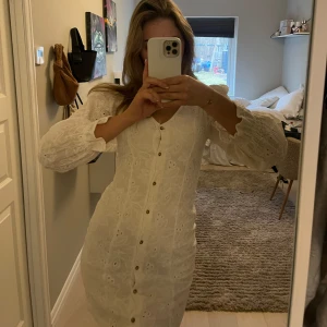 Vit klänning med broderad spets - Säljer en elegant vit klänning med broderad spets och knappar framtill. Perfekt till studenten nu!✨storlek 34 men passar mig oftast har S-M