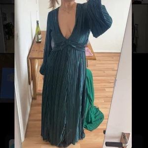 Grön långklänning - Snygg grön långklänning med djup v-ringning och långa ärmar. Nyskick, använd en gång. Köpt för ca 1000💚💚strl 40 men sitter bra på mig som brukar ha 38! skriv för fler bilder på! 