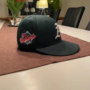Limited new era keps - Snygg grön keps från New Era med broderad logga på framsidan och en patch på sidan. Perfekt för sportiga tillfällen eller som en stilren accessoar.
