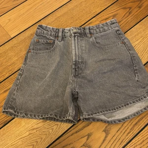 Grå jeansshorts - Säljer ett par klassiska grå jeansshorts med fem fickor och knappgylf. Perfekta för en avslappnad stil. De har en bekväm passform och är tillverkade i slitstarkt denim.