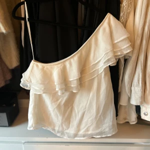 Vit offshoulder topp från Bubbleroom - Säljer en stilren vit offshoulder topp från Bubbleroom med volangdetaljer.Toppen har en luftig passform.