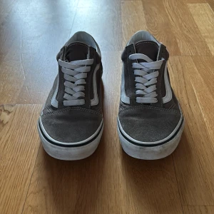 Grå sneakers från Vans - Snygga gråa Vans sneakers med vit sula och klassisk vågig sidodetalj.