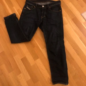  Jeans Diesel Regular W32 - Snygga mörkblå jeans från Diesel med klassisk femficksdesign och kontrastsömmar. Jeansen har en diskret logga på myntfickan och en etikett bak. Perfekta för en stilren och Grisch look. W 32 regular fit