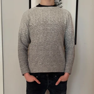 Grå tröja från COS - Säljer en stilren grå tröja från COS. Tröjan har en melerad design och är långärmad med en rund halsringning. Perfekt för en avslappnad och modern look. Modellen är 180cm. 