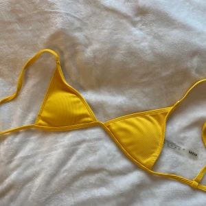 Gul bikini från SHEIN - Snygg gul bikini från SHEIN i ribbat material. Toppen har trekantsform med knytband och matchande botten med smal passform. Perfekt färg när man blivit solkysst 😊 ALDRIG ANVÄNT. 