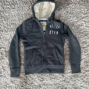 Hollister fodrad hoodie - Tja! En grå hoodie från Hollister med dragkedja och mjukt foder i luvan. Sitter hur skönt som helst! Skick 10/10. Pris kan diskuteras🌟