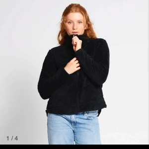 Fleece - Mysig svart fleece med dragkedja framtill. Perfekt för kyliga dagar med sin fluffiga och varma design. Tröjan har en hög krage och långa ärmar, vilket gör den extra varm och bekväm.