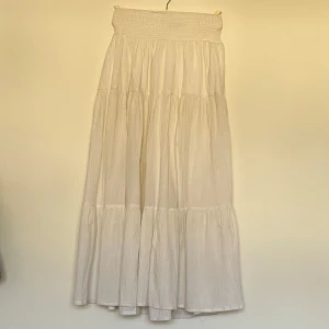 Vit långkjol med slits - Vit långkjol med en snygg slits på sidan. Kjolen har en smockad midja som ger en bekväm passform. Den kan användas som både högmidjad och lågmidja. (Jag är 174)🤍