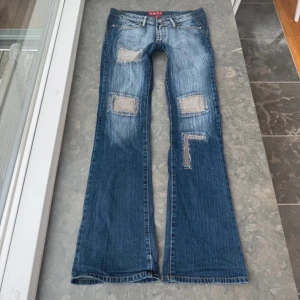 Lågmidjade bootcut jeans - Snygga blåa lågmidjade bootcut jeans från W&M med unika patchar på framsidan och bakfickorna. Köpta på plick och ej använda då de ej passade mig. 💝Midjemått tvärsöver: 42 cm, midjehöjd: 21 cm, innerbenslängd: 84 cm. Pris kan diskuteras!💞