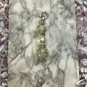 Silverfärgat hänge med pärlor - Elegant hänge med två glittriga silverkulor och en vit pärla i mitten. Perfekt för att ge en extra touch till ditt smycke. Fästes enkelt med en karbinhake.