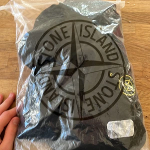 Svart hoodie från Stone Island - Säljer en stilren svart hoodie från Stone Island med dragkedja och huva. Tröjan har en ikonisk logga på ärmen och är perfekt för en casual look. Den är tillverkad i ett mjukt material som ger en bekväm passform. Helt ny för liten för mig pris kan diskuteras om.