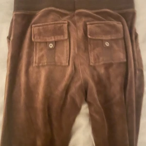 Bruna juicy  mjukisbyxor med fickor och snörning - Mysiga bruna mjukisbyxor med stora fickor både fram och bak samt snörning i midjan. Byxorna har en loose passform och är perfekta för en avslappnad stil.