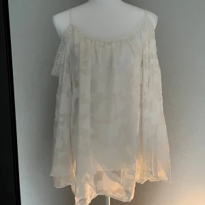 Vit blommig ärmlös blus med spetsdetaljer - Säljer en luftig vit blus med blommigt mönster. ingen lapp men passar S-M