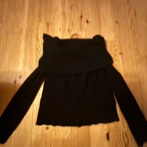 Svart offshoulder stickad tröja från H&M - Säljer en svart stickad offshoulder-tröja från H&M i storlek M. Tröjan har långa ärmar och en bred, vikt krage som sitter snyggt över axlarna. Perfekt för dig som vill ha en trendig och bekväm look.