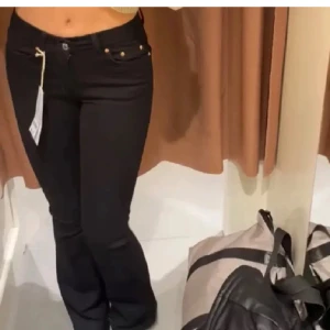 Svarta bootcut jeans - Snygga svarta jeans med bootcut passform och låg midja. Klassisk femficksmodell med knapp och dragkedja framtill. Perfekta för dig som vill ha en tidlös och stilren look.