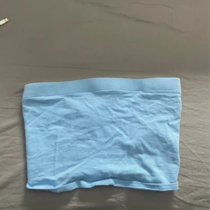 Ljusblå tubtopp - Säljer en enkel och stilren ljusblå tubtopp. Perfekt att matcha med jeans eller kjol för en avslappnad look. Mjuk och stretchig resår upptill för bra passform.