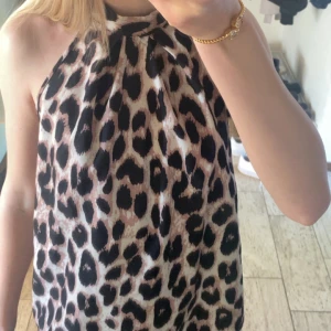 Leopardmönstrad topp - Säljer en snygg halterneck topp med leopardmönster. Toppen är ärmlös och har en hög hals med knytning i nacken.