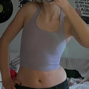 Ljuslila ribbat croppat halterneck linne - Säljer ett ljuslila ribbat croppat halterneck linne /topp från H&M:s Divided-kollektion. Toppen har smala axelband och är figurnära med stretchigt material. Perfekt för sommar och varma dagar. 