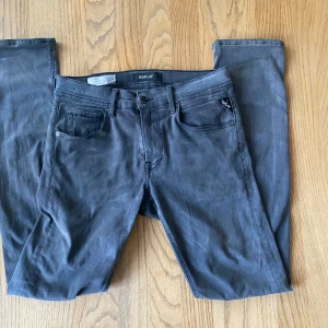 Replay Grover Jeans  - Säljer ett par grå Replay Grover Hyperflex jeans med klassisk femficksdesign och svarta detaljer. Jeansen har raka ben och normal passform, samt diskret broderi på bakfickorna. Perfekta för dig som gillar stilrena och bekväma jeans.