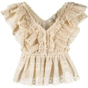Beige spetsblus med volang - Supersöt beige blus med v-ringning och volanger på axlarna. Blusen är dekorerad med spetsdetaljer och har en feminin, romantisk look. Perfekt för dig som gillar boho-stil och vill ha något extra till outfiten.