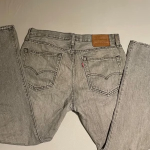 Grå Levi's 551 jeans W32 L32 - Säljer ett par grå Levi's 551 jeans med klassisk femficksdesign och raka ben. Jeansen har läderpatch bak i midjan och den ikoniska röda Levi's-taggen på bakfickan. Perfekta för dig som gillar vintagekänsla och tidlös stil.