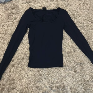 Mörkblå långärmad topp från Gina Tricot - Säljer en mörkblå långärmad topp från Gina Tricot i storlek XXS. Toppen har en rundad urringning och är figurnära i modellen. Perfekt att styla till jeans eller kjol.