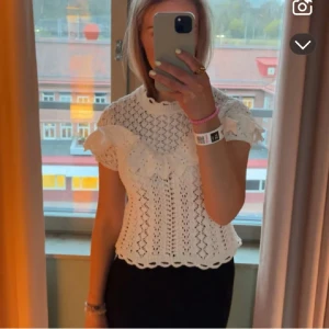 Vit stickad blus med volang - Säljer en söt vit stickad blus med volangdetaljer och korta ärmar. Blusen har ett fint hålmönster och rund halsringning. Perfekt för dig som gillar romantisk stil!💞💞