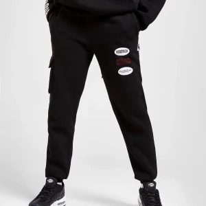 Svarta mjukisbyxor med patch-detaljer - Svarta mjukisbyxor med coola broderade patches på låret. Byxorna har en normal passform och resår vid bensluten. Perfekta för en avslappnad streetstyle-look.