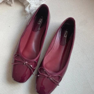 Vinröda ballerinaskor med rosett - Vinröda glansiga och söt rosettdetalj framtill. 