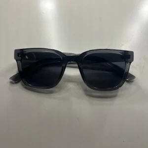 Svarta solglasögon med fyrkantig båge - Stilrena svarta solglasögon med fyrkantig båge och mörka glas. Perfekta för att ge en cool vibe till din outfit. Passar dig som gillar klassisk och enkel design. Dem har även UV 400 