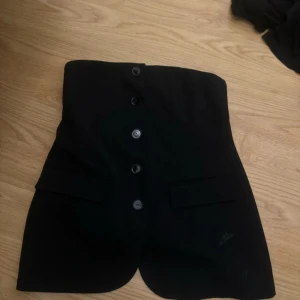 Svart kostym topp med knappar från Zara - Säljer en svart topp från  Zara med  knappar framtill. Toppenhar två ficklock framtill som ger en snygg detalj. 