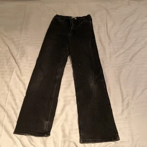 Svarta jeansbyxor från Lindex - Svarta jeansbyxor från Lindex med raka ben och klassisk femficksdesign. Byxorna har normal passform och är tillverkade i ett slitstarkt jeanstyg. Perfekta för dig som gillar en enkel och tidlös stil. Dessa byxor har två små hål vid vänstra knät men märks inte av!