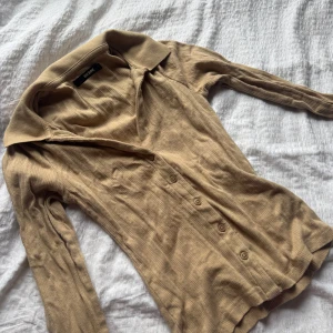 Beige ribbad pikétröja från Bik Bok - Säljer en beige ribbad pikétröja från Bik Bok med långa ärmar och knappar framtill. Tröjan har krage och är i mjukt stickat material. Den är för liten på mig så har alltså inte använt den så mycket, skriv privat för mer bilder💗